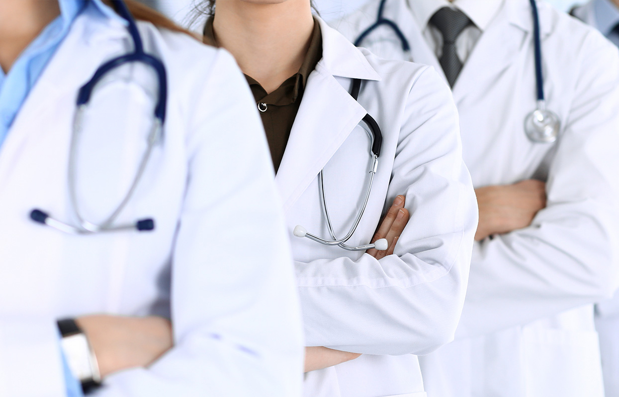 The image depicts a group of healthcare professionals in lab coats standing side by side, looking forward with a serious expression.