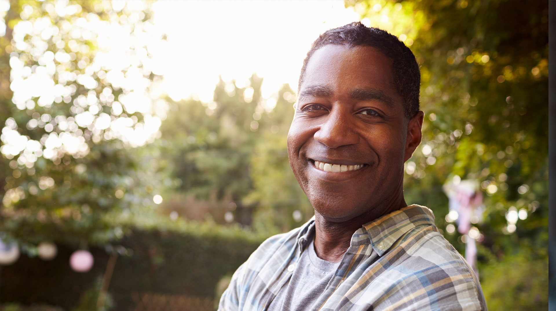 The image features a smiling man standing outdoors, dressed in casual clothing.